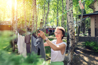 Young woman standing by tree in forest
