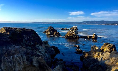 Rocks in sea against blue sky