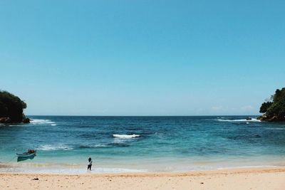 Woman wading in sea against clear blue sky