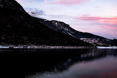 Scenic view of lake by snowcapped mountains against sky during winter