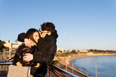 Young couple embracing on a balcony facing the sea