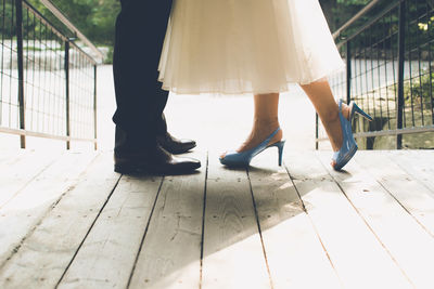 Low section of couple standing on boardwalk