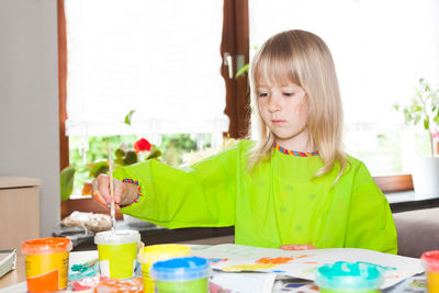 Girl painting on paper while sitting at home