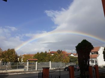 Rainbow over buildings in city against sky