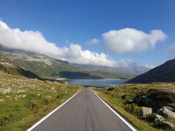 Road leading towards mountains against sky