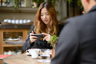 Young woman using phone in restaurant