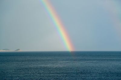 Scenic view of rainbow over sea against sky