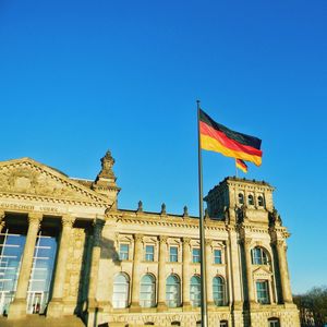 Low angle view of flags against clear blue sky