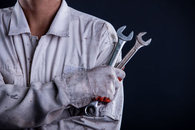 Midsection of woman holding white dress against black background