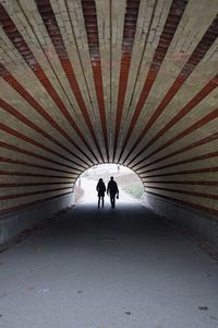 Silhouette people walking in tunnel