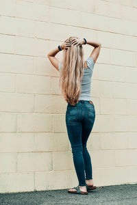 Full length of woman standing against wall