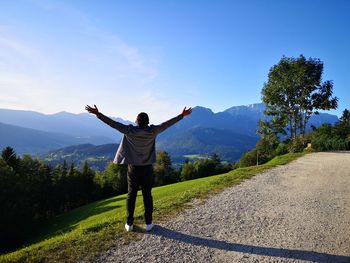 Rear view of man standing on mountain against sky