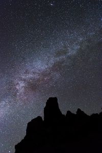 Low angle view of silhouette rock against sky at night