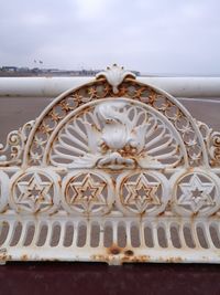 Close-up of ornate railing by sea against sky