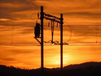 Silhouette electricity pylon against romantic sky at sunset