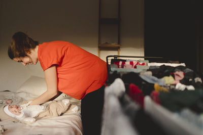 Side view of man sitting on bed at home