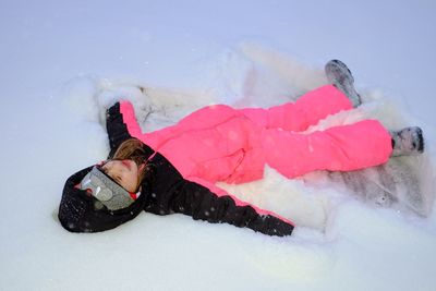 High angle view of girl making snow angel on field