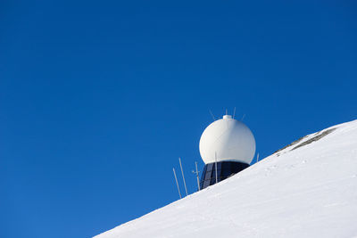 Low angle view of snowcapped mountain against clear blue sky