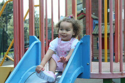 Happy girl playing on slide at playground