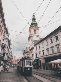 Cars on street amidst buildings in city against sky