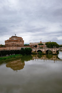 Arch bridge over river against cloudy sky