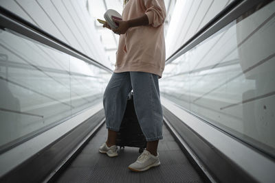 Legs of woman standing on escalator at airport