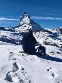 Rear view of man sitting on snow covered mountain