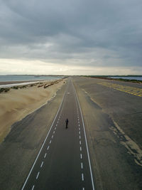 A man with long hair skating on a empty road in europe