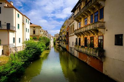 Canal amidst buildings against sky