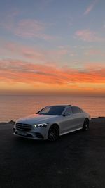 Car on sea shore against sky during sunset