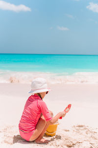 Midsection of woman sitting on beach against sky