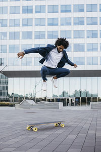 Spain, barcelona, young businessman doing skateboard tricks in the city