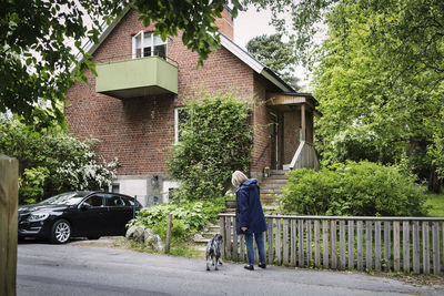 Senior woman and dog standing outside house
