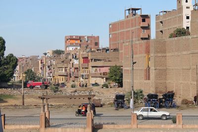 Cars on road by buildings against clear sky