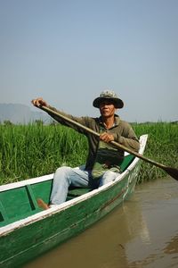 Portrait of man sitting on boat against sky