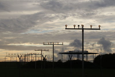 Silhouette of landing lights against sky during sunset