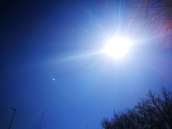 Low angle view of sun shining in blue sky