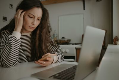 Woman watching on mobile screen with unhappy face reading messages bad