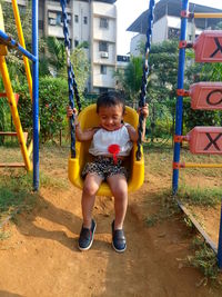 Smiling girl sitting on swing in playground