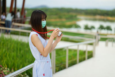 Woman holding umbrella standing by railing