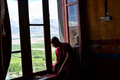 Side view of girl looking through window