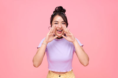 Portrait of smiling young woman against pink background