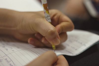 Cropped hand of person writing on book