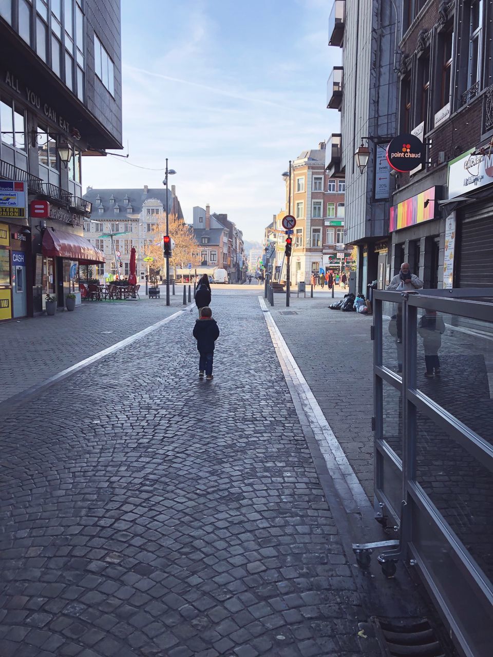 building exterior, city, built structure, architecture, street, one person, the way forward, direction, transportation, footpath, real people, rear view, day, cobblestone, full length, lifestyles, walking, building, city life, diminishing perspective, outdoors, paving stone