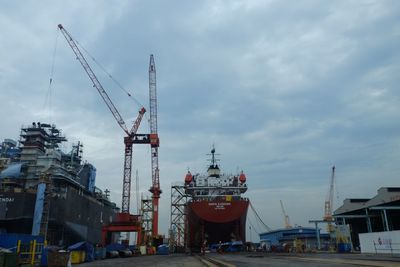 Cranes at harbor against sky