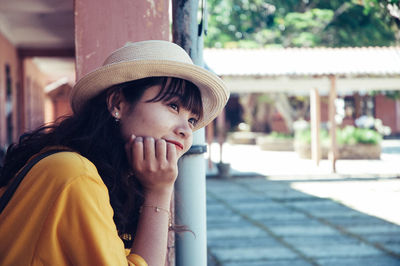 Smiling young woman in sun hat looking away