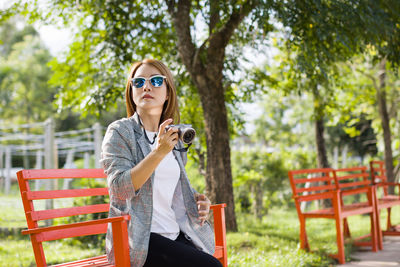Portrait of young woman wearing sunglasses while sitting outdoors