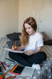 The girl after school plays at home, draws with pencils and felt-tip pens