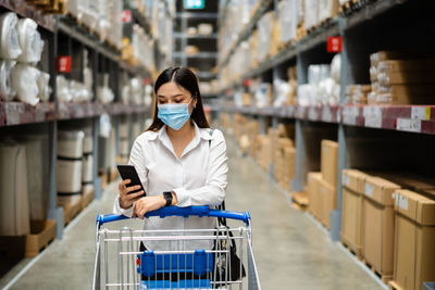 Full length of man using mobile phone in store