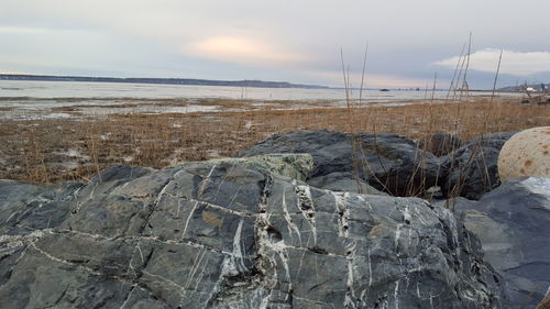 Rocks at beach against sky during winter